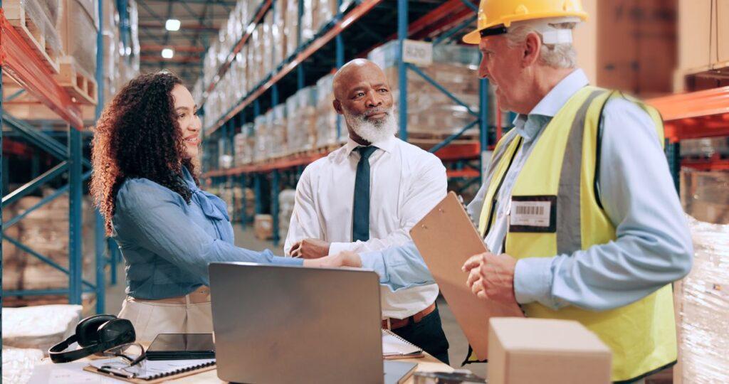 Besprechung und Handschlag im Lager zwischen Einkauf und Logistik – zeigt praktische Umsetzung von verhandlungstraining im einkauf