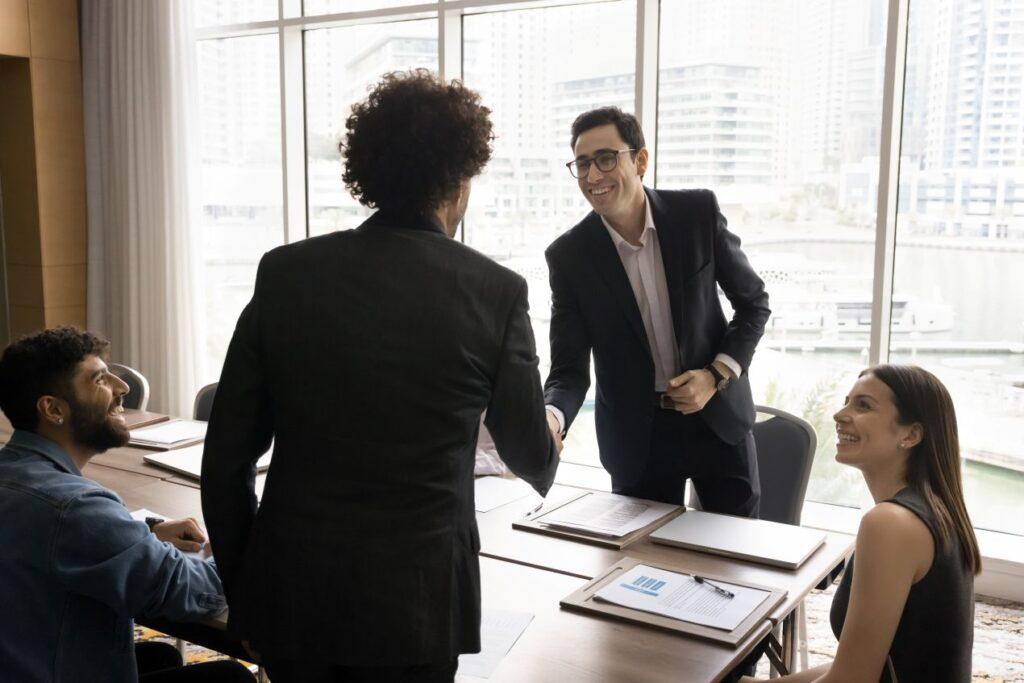Businessmeeting mit Handschlag am Tisch – zeigt erfolgreiche geschaeftliche Verhandlung durch verhandlungstraining im einkauf