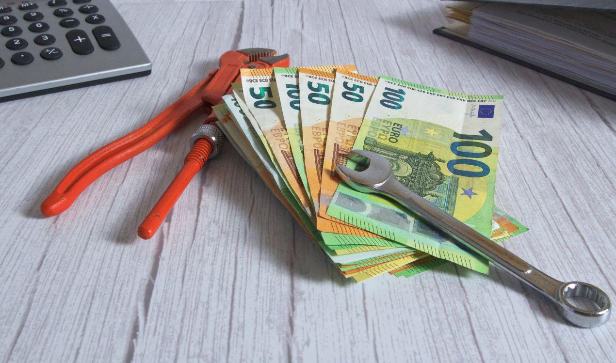 euro-geldscheine mit werkzeug auf schreibtisch – kosten einer dachsanierung von aussen berechnen und absetzen