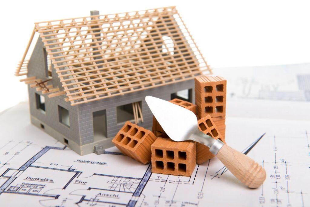 modellhaus mit ziegeln und bauplan – dachsanierung von aussen vorbereiten und strukturieren