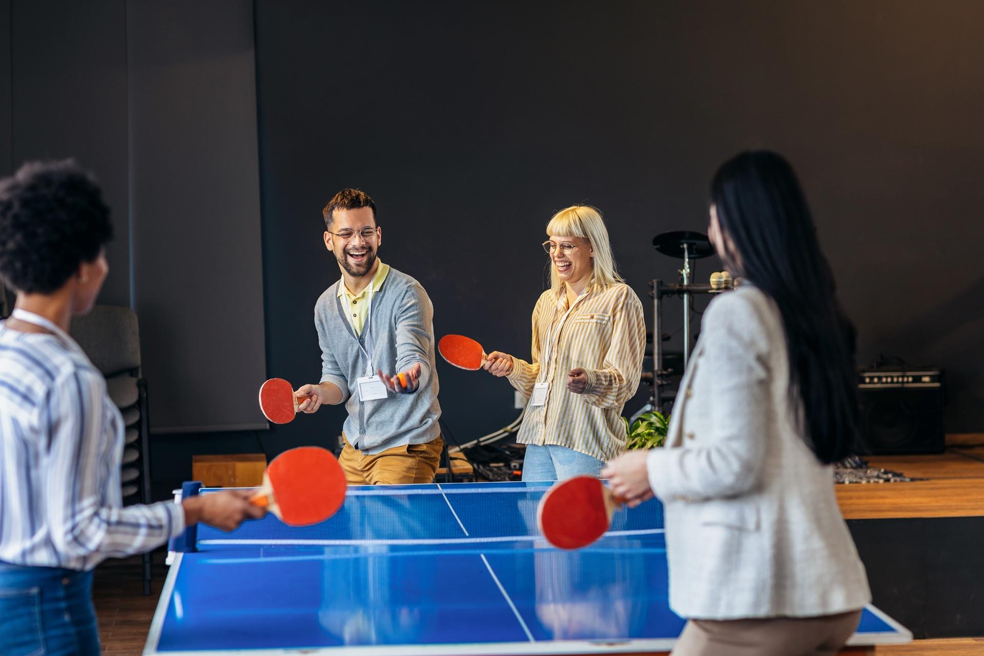 Lachendes Team spielt gemeinsam Tischtennis im Pausenraum | Stahlwandpool oval Erdeinbau